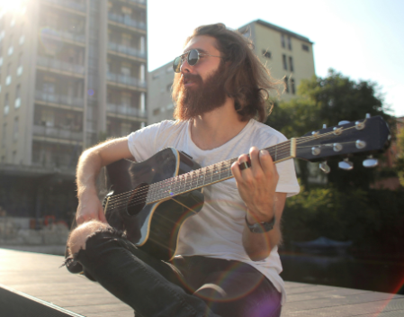 guy playing and learning acoustic guitar outside