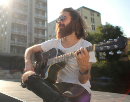 guy playing and learning acoustic guitar outside 